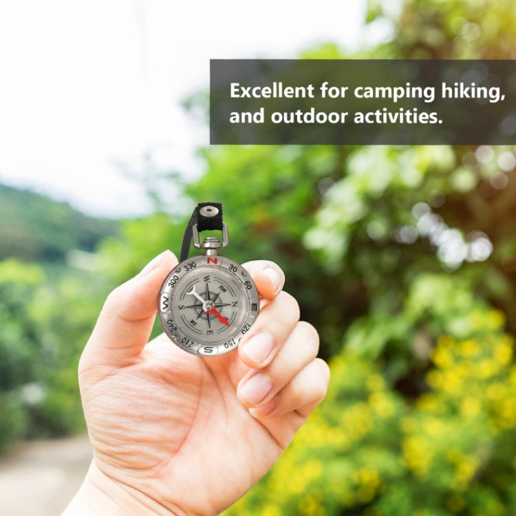 Mini metal compass on black keyring held in hand, red needle pointing