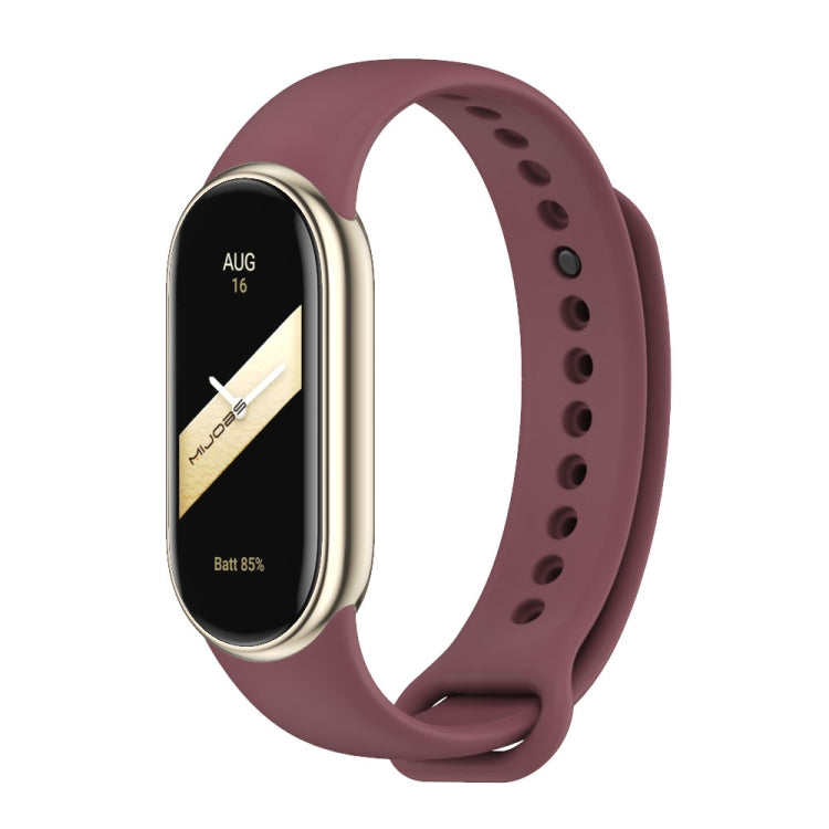 Burgundy silicone watch band with adjustable holes and metal buckle, shown with a fitness tracker