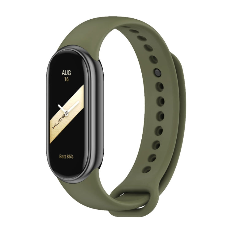 Olive green silicone watch band with adjustable holes and metal buckle, shown with a fitness tracker