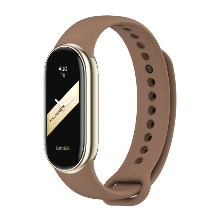 Brown silicone watch band with adjustable holes and metal buckle, shown with a fitness tracker