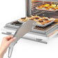 Hand holding a silver fish-shaped oven rack push-pull stick over baked food