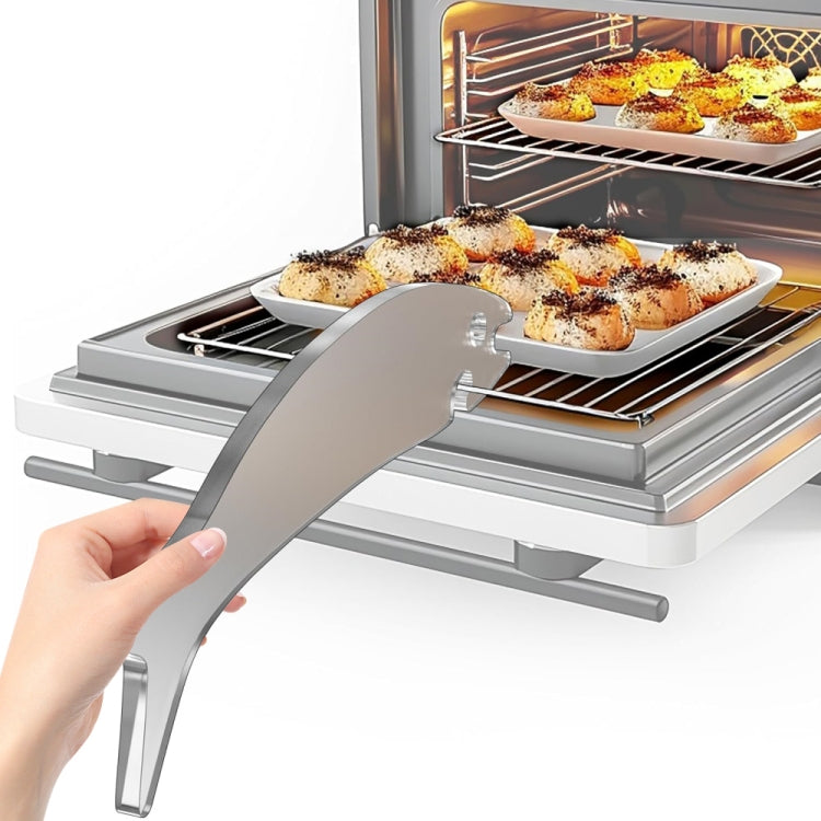 Hand holding a silver fish-shaped oven rack push-pull stick over baked food