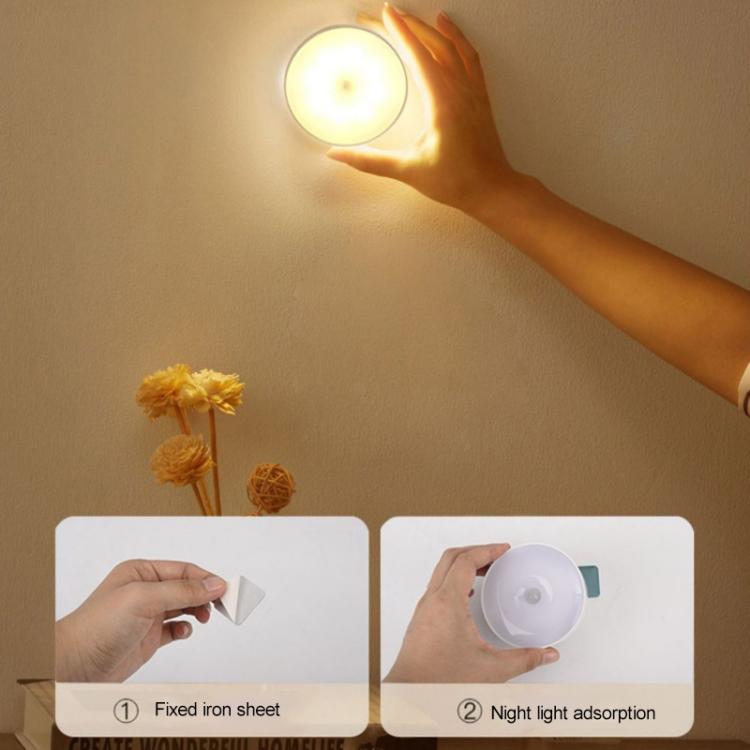 Hand holding a round LED night light with warm glowing lens and gray outer ring