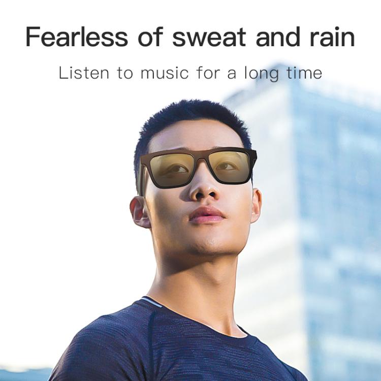 Black smart audio glasses with amber-tinted lenses worn by a man.