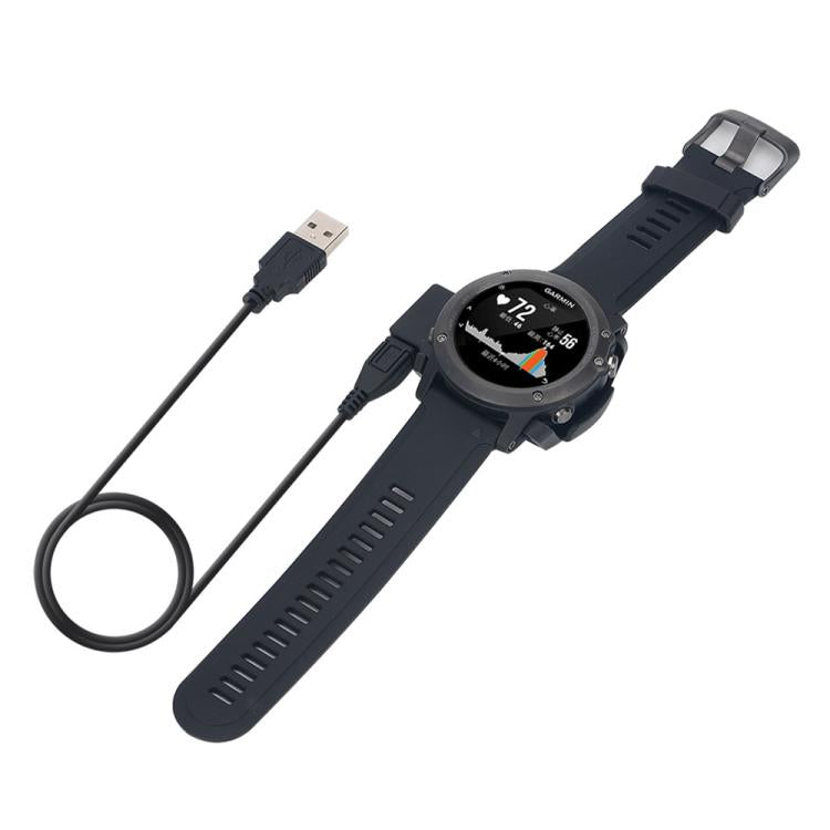 Black Garmin smartwatch connected to its USB charging cable