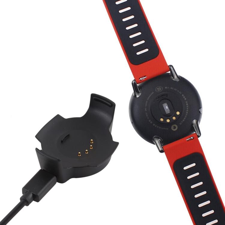 Black charging cradle beside the back of a smartwatch with a red band