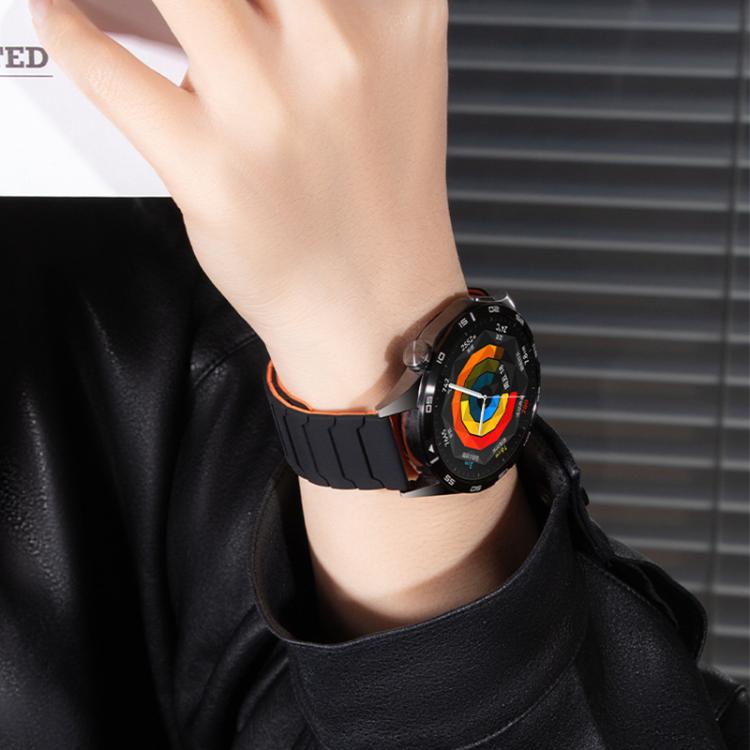 xDfind black silicone watch band with orange edging, worn on a wrist