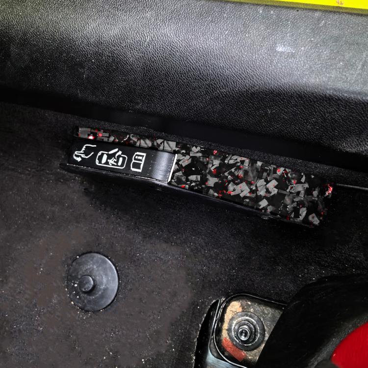 Door lock switch decorative sticker, black carbon-fiber style with red flecks, installed