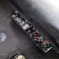 Door lock switch decorative sticker, black carbon-fiber style with red flecks, close-up