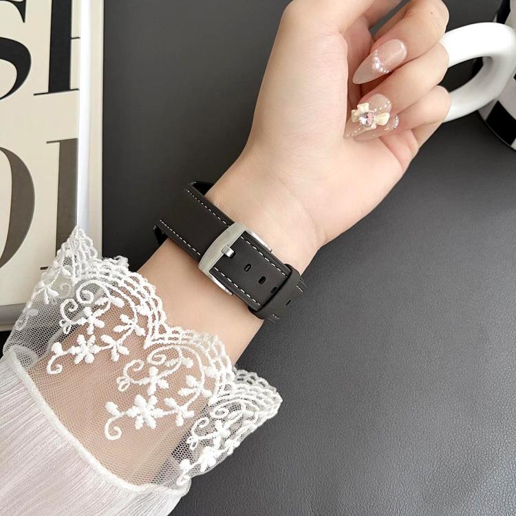 Black leather watch band with white stitching and silver buckle worn on a wrist.