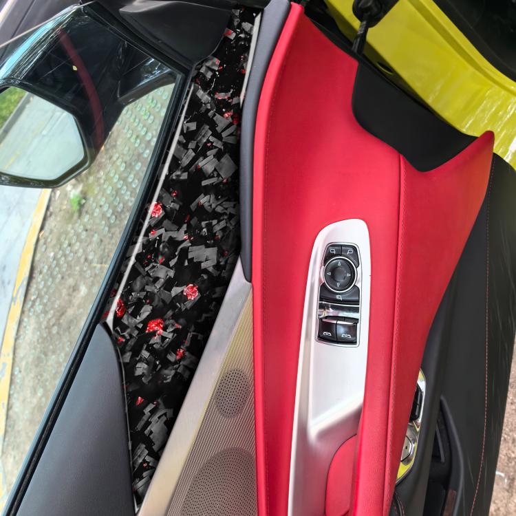 Black carbon-fiber door panel decals with red fleck pattern applied on car door trim