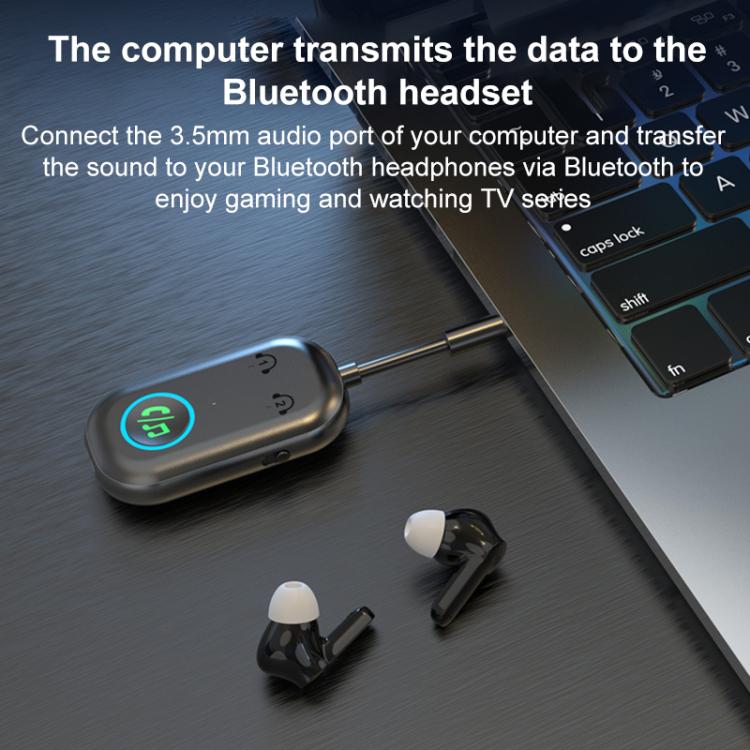 Bluetooth AUX audio adapter near laptop with 3.5mm plug and blue LED button