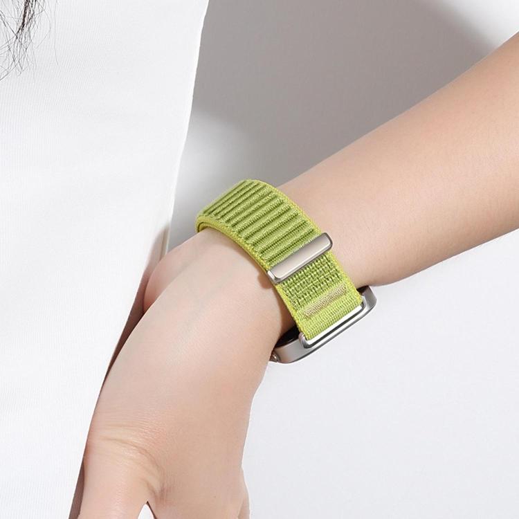 Green woven nylon watch band with metal loop closure, worn on the wrist