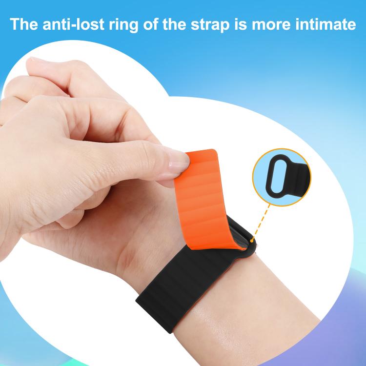 Black and orange silicone watch band worn on a wrist, showing its retaining loop.