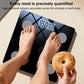 Smart body fat scale in use with feet on platform and donut held near display
