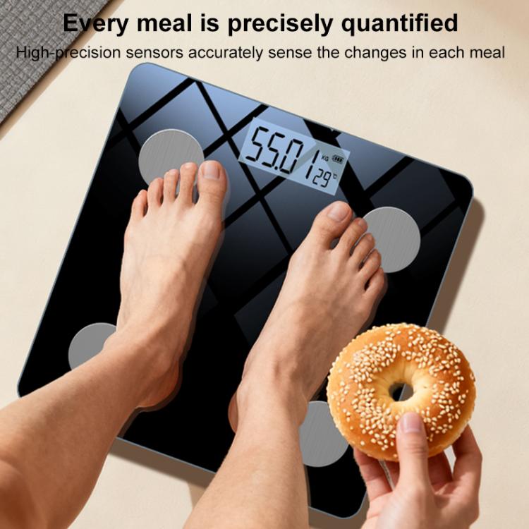 Smart body fat scale in use with feet on platform and donut held near display