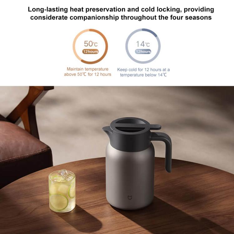 Titanium insulated kettle with black lid, silver body on wooden table with glass