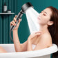 Handheld shower head in use, releasing a wide mist spray toward a person