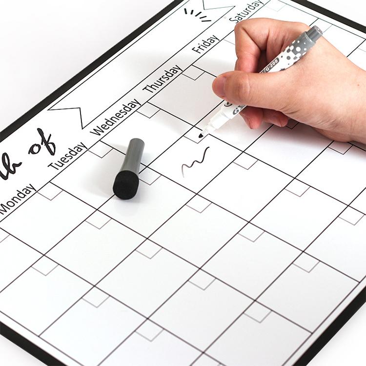 Monthly calendar magnetic refrigerator message board being written on with marker