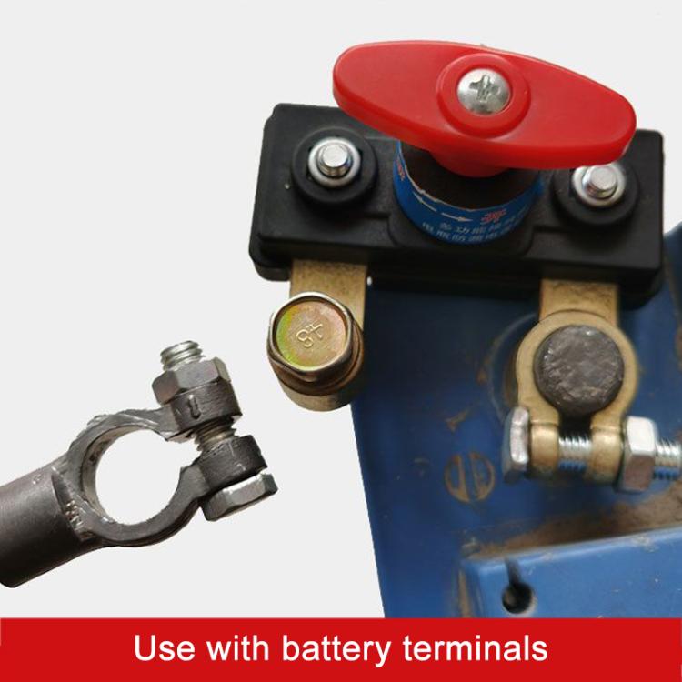 Close-up of car battery disconnect switch with red lever and copper cable terminals
