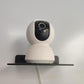 Wall-mounted acrylic shelf rack, black, holding a small security camera device