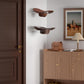Wall-mounted clear acrylic cowboy hat rack with two brown hats on the wall