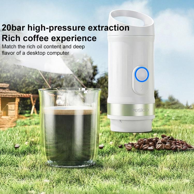 White portable coffee machine with blue button over a clear mug