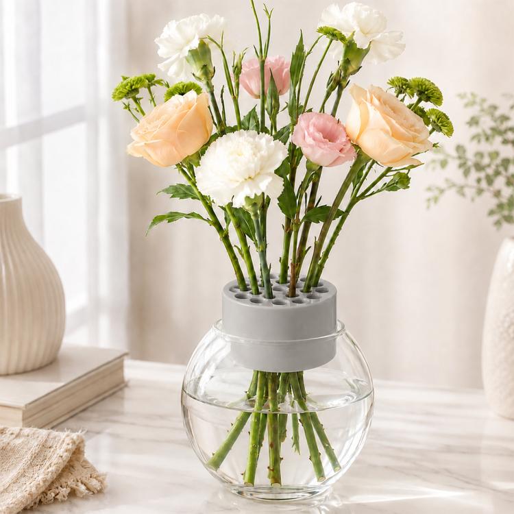 Grey plastic flower stem holder cylinder with round stem holes on a clear glass vase