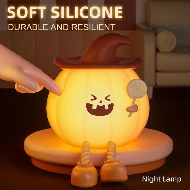 Silicone pumpkin night lamp with jack-o’-lantern face, soft orange glow, brown hat, toy hands