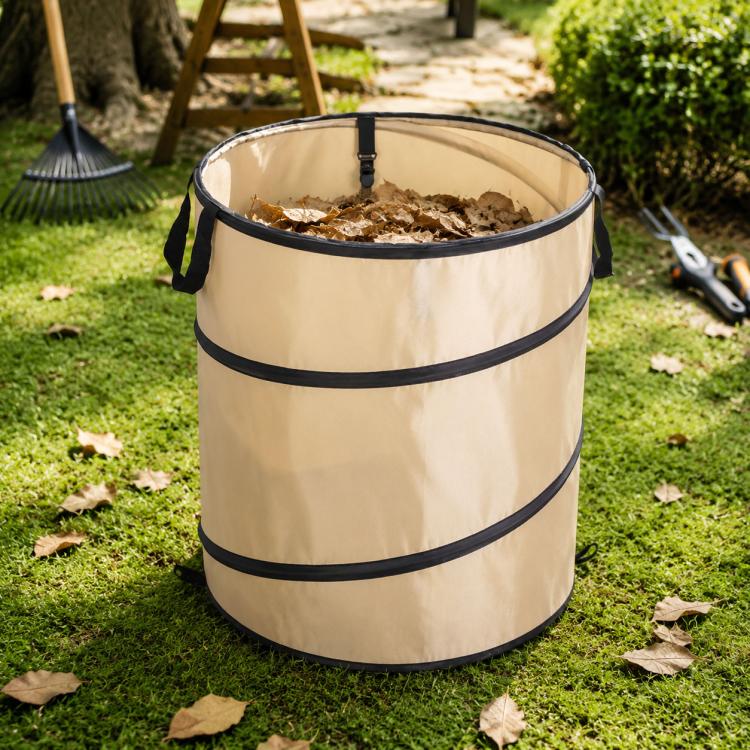 Beige foldable camping bucket with leaves inside and black carrying straps