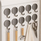 Multiple round magnetic metal wall hooks arranged on a wall, each with a curved hanger