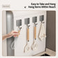 Hand holding a magnetic metal wall hook with curved hanger and wooden handle