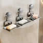 Three grey suction cup soap and sponge holders with drainable metal trays