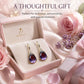 Teardrop dangle earrings in a gift box: gold-tone hooks with purple crystal and clear accents.