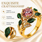 Gold-tone floral ring with pink gemstone center, green enamel leaves, sparkling crystals