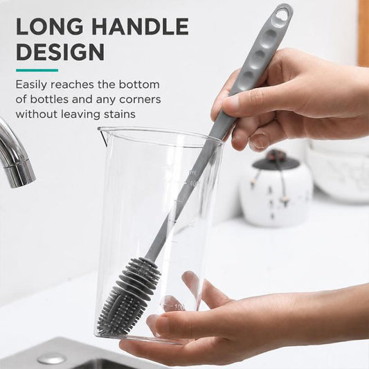 Long-handle silicone cup cleaning brush with gray bristle head inside clear glass