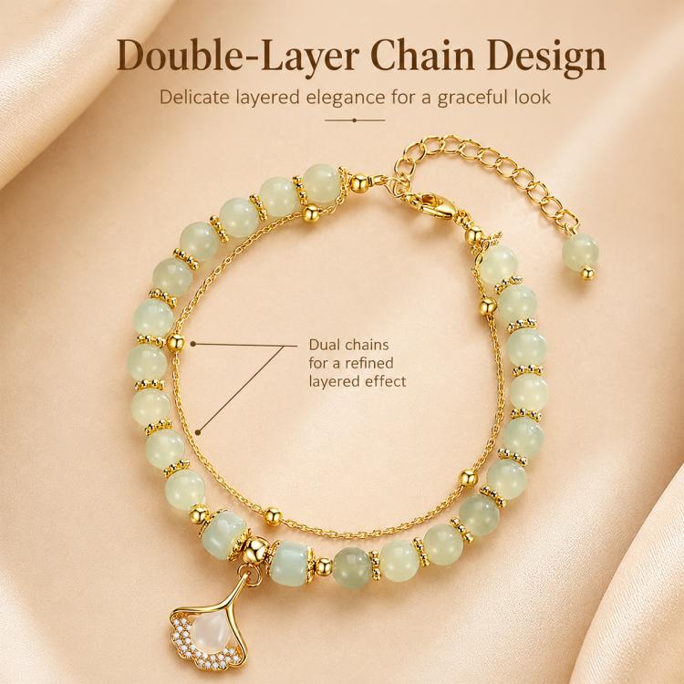 Gold double-chain charm bracelet with pale green bead strands and a leaf pendant.