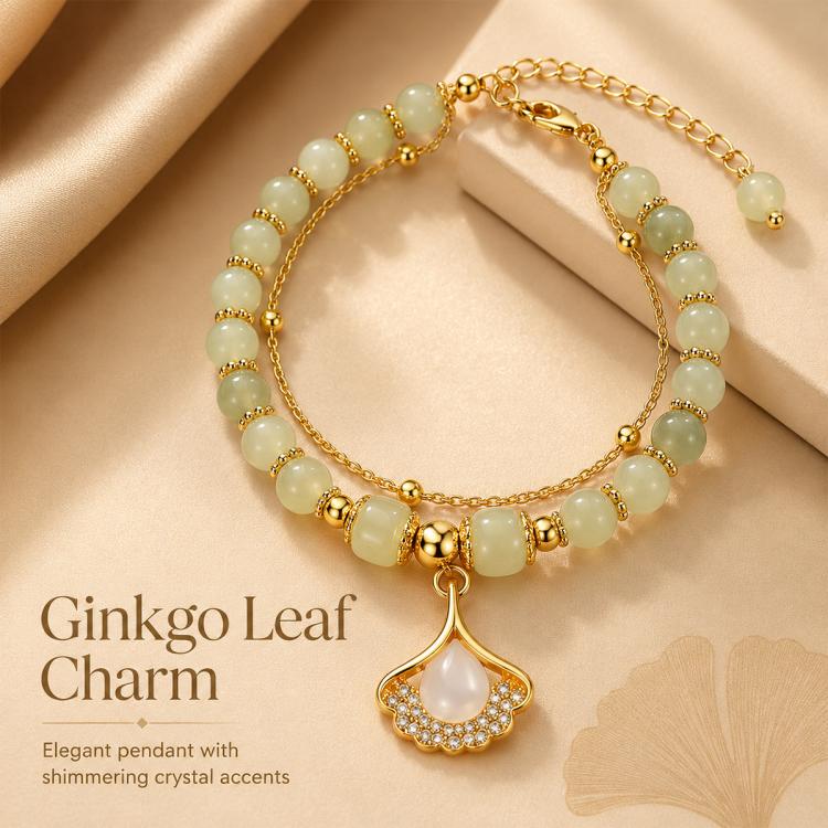 Gold beaded charm bracelet with pale green round beads and a ginkgo-like leaf pendant.