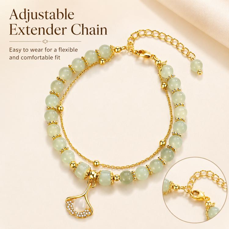 Gold adjustable charm bracelet with pale green beads and a leaf pendant; extender chain shown.