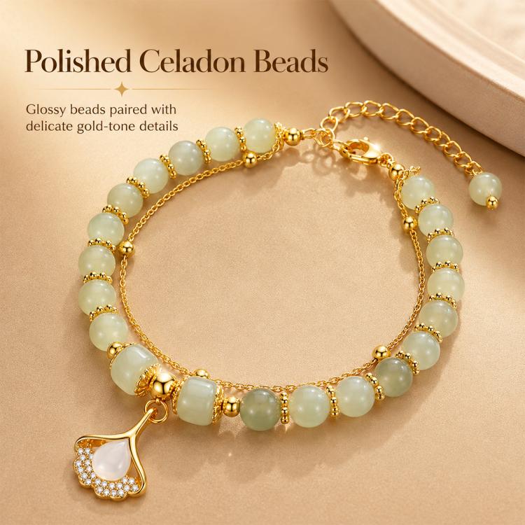 Gold-tone charm bracelet with polished pale green beads and a teardrop leaf pendant.