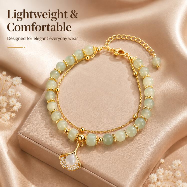 Gold-toned lightweight charm bracelet with pale green beads and a leaf pendant charm.