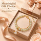 Gold-tone beaded charm bracelet in gift box with pale green beads and leaf pendant charm.