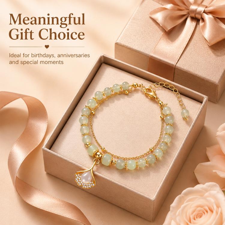 Gold-tone beaded charm bracelet in gift box with pale green beads and leaf pendant charm.
