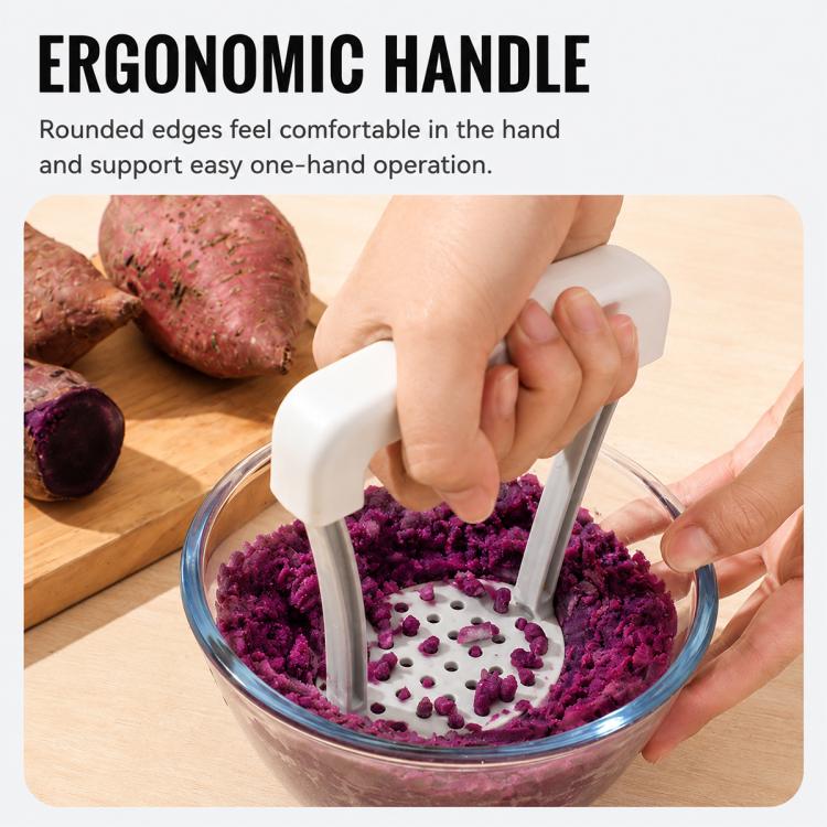 Manual potato masher mashing purple vegetables in a glass bowl; perforated base
