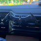 Bat-style car phone mount attached to air vent, black design with yellow emblem