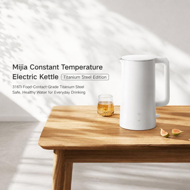 White electric kettle standing on a table with a cup in front.