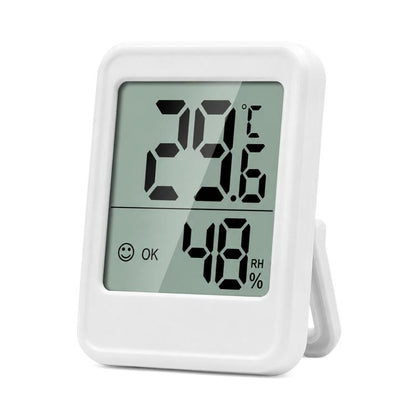 Indoor digital thermometer and hygrometer with white frame and LCD showing temp and humidity