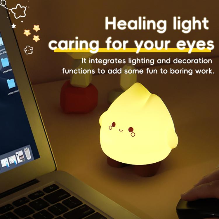 Yellow glowing flame night light on a desk with cute face and round cheek dots