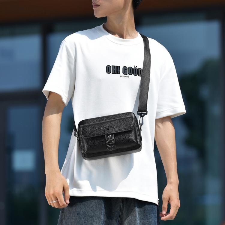 Black textured lychee crossbody bag with front buckle flap, worn crossbody