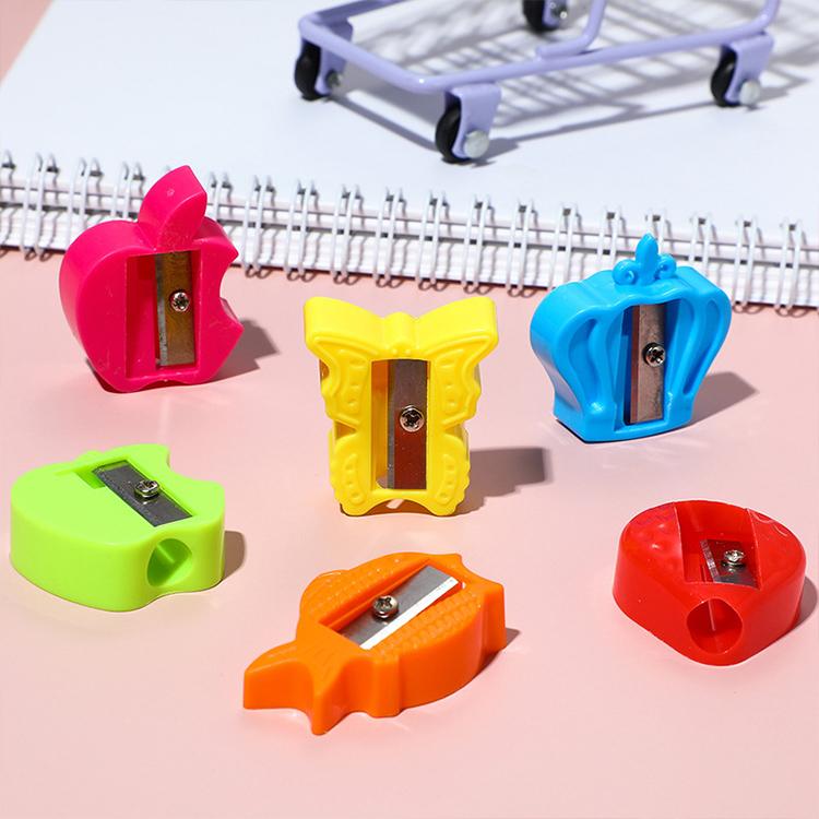 Assorted color single-hole pencil sharpeners with metal blades on pink background